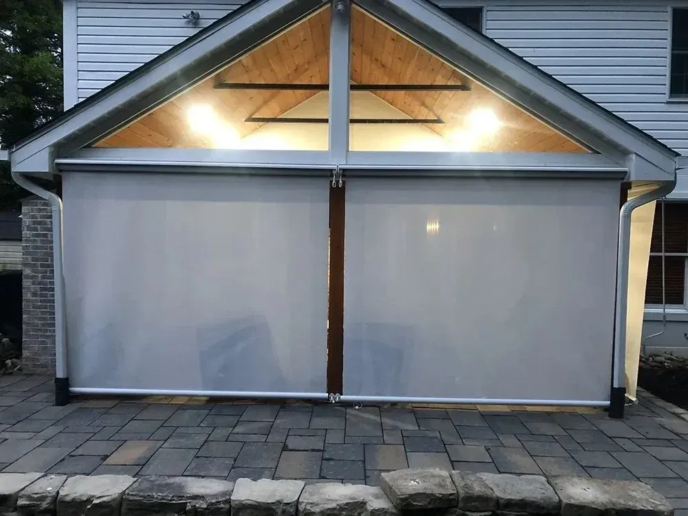 Outdoor patio with retractable shades; wooden ceiling with lights; brick patio flooring.