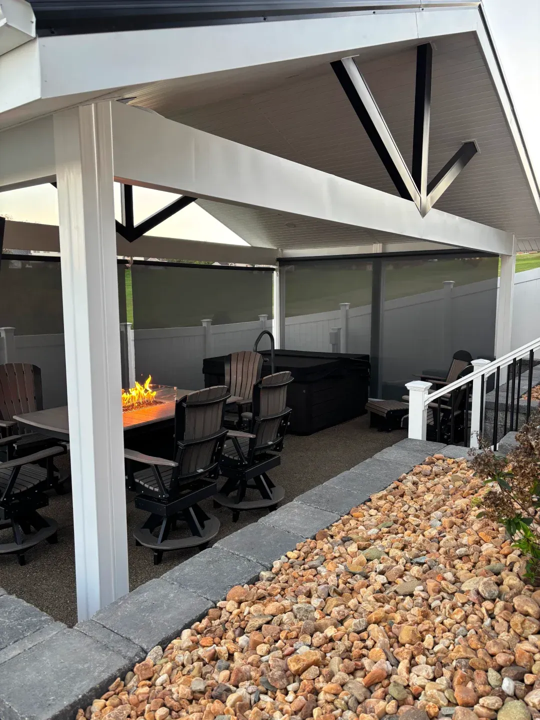Outdoor patio with seating, fire pit, hot tub, and overhead shelter.