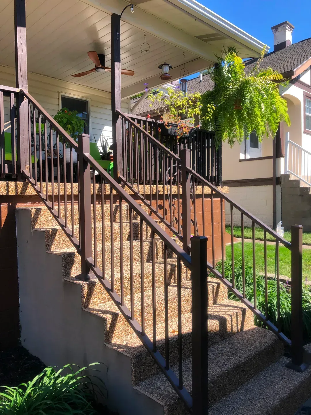 Brown metal railing along outdoor stairs leading to a porch.