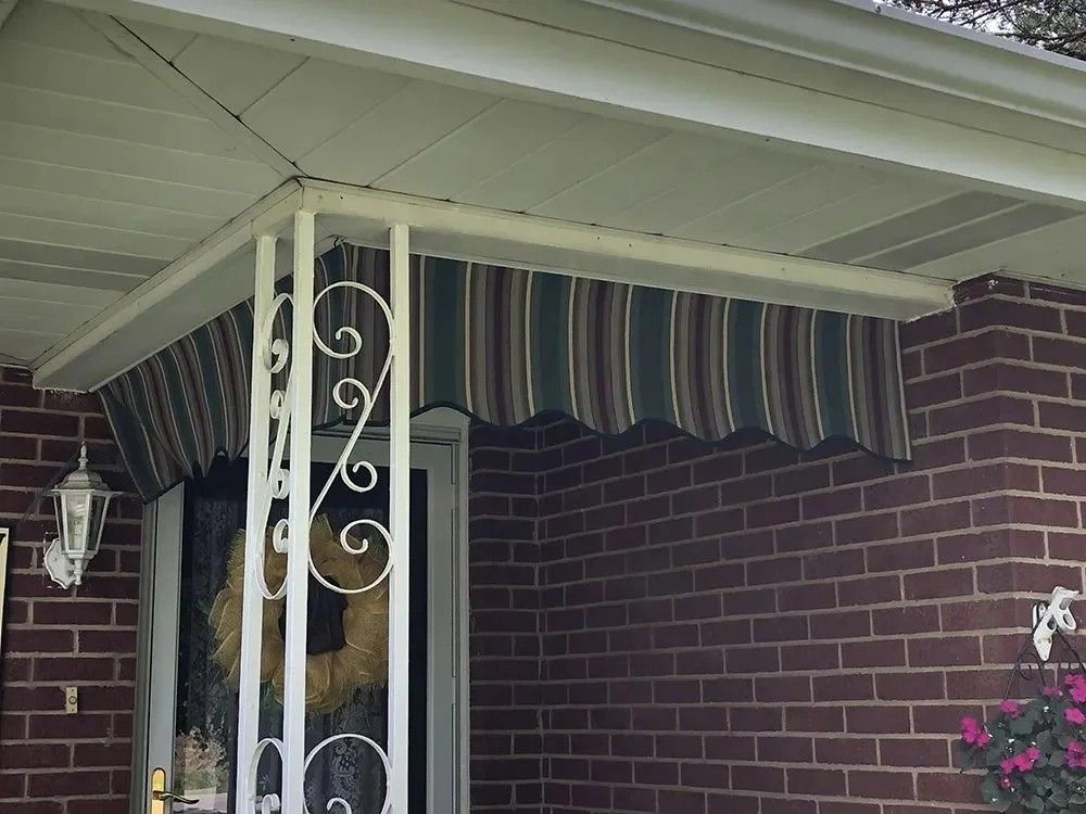 Striped awning over a brick entrance, supported by white metal columns.