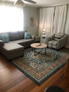 Living room with gray sectional, striped armchair, round coffee table, and patterned rug.