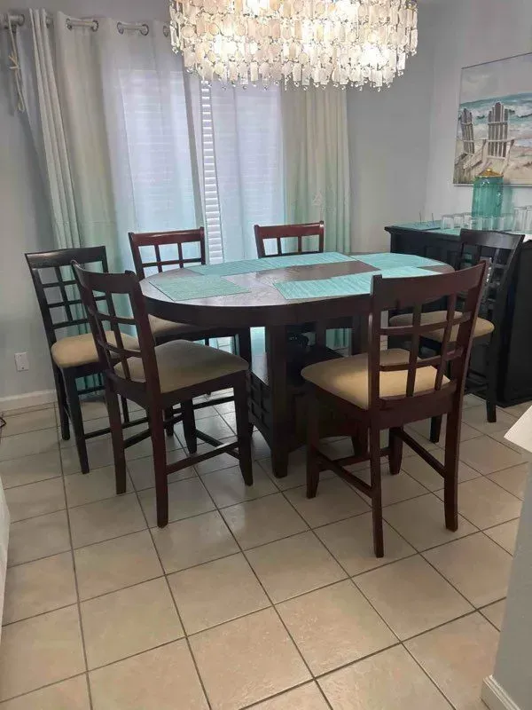 Dining room with dark wood table, chairs, and chandelier. Light blue tablecloth.