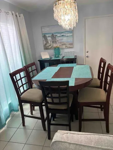 Dining room with table and chairs, turquoise accents, artwork, and chandelier.