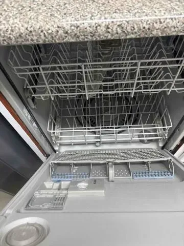 Open dishwasher interior with top and bottom racks visible, ready for loading.