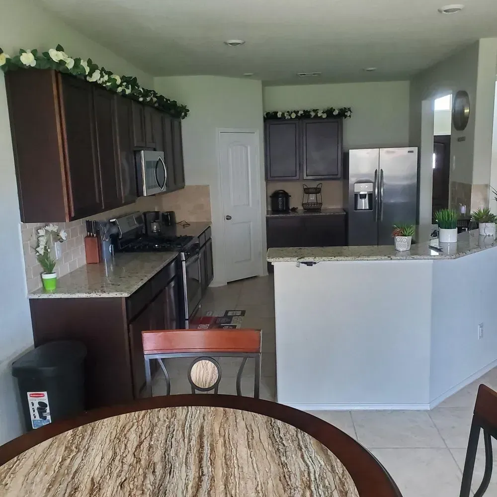 A kitchen with dark cabinets, stainless steel appliances, and a round table.