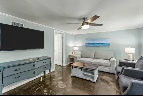 Living room with light blue walls, gray furniture, TV, and ceiling fan.