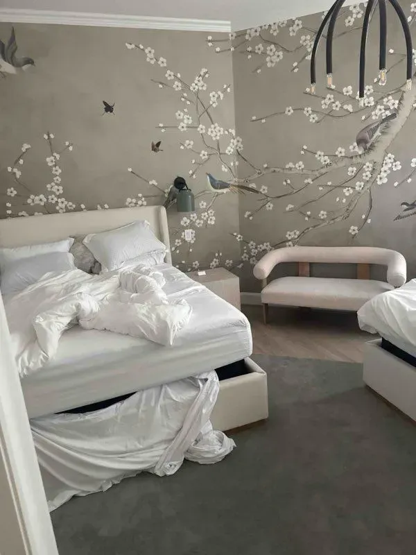 Bedroom with white bed, floral wallpaper, small sofa, and gray carpet.