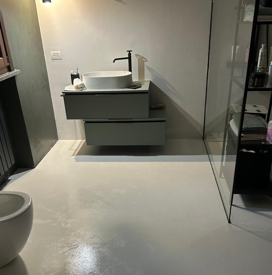 Ristrutturazione del bagno: zona vasca parzialmente demolita, nuova pavimentazione e moderno mobile lavabo bianco.