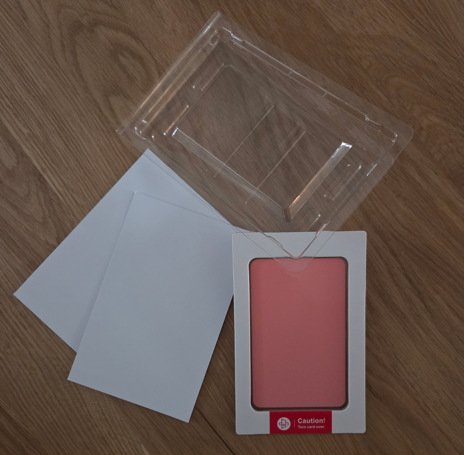 Een stempelkussenset met babyvoetafdrukjes, inclusief een vierkantje zwarte inkt, twee witte vellen karton en een doorzichtige plastic verpakking.