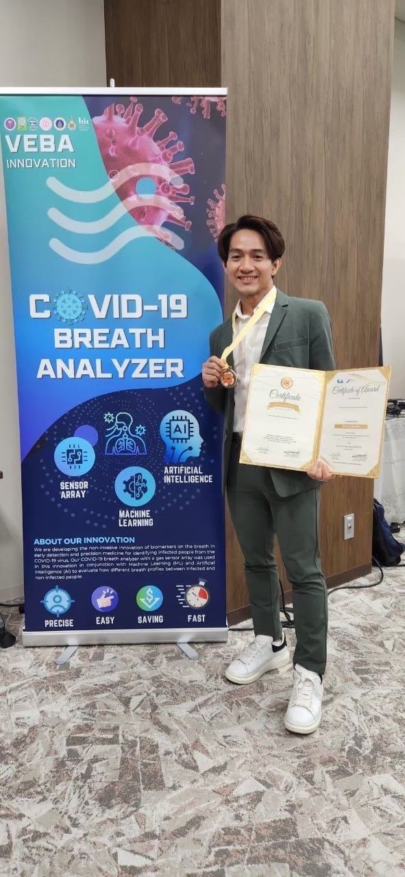 A man in a suit is standing in front of a banner holding a certificate.