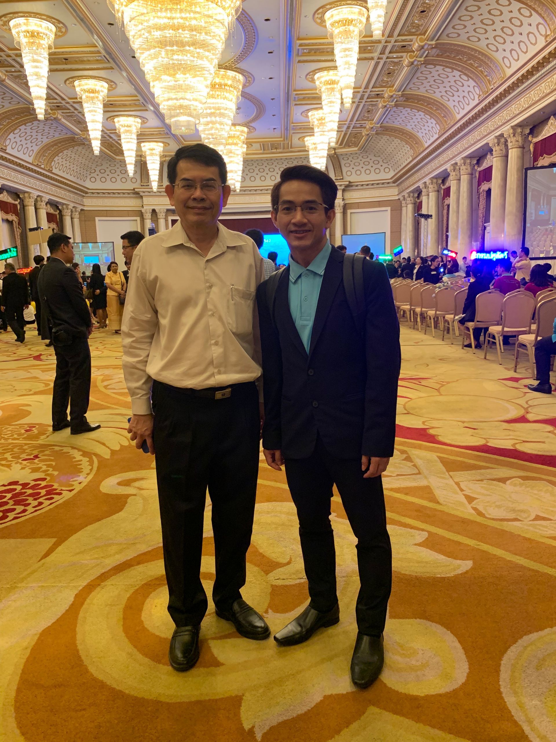 Two men are posing for a picture in a large room