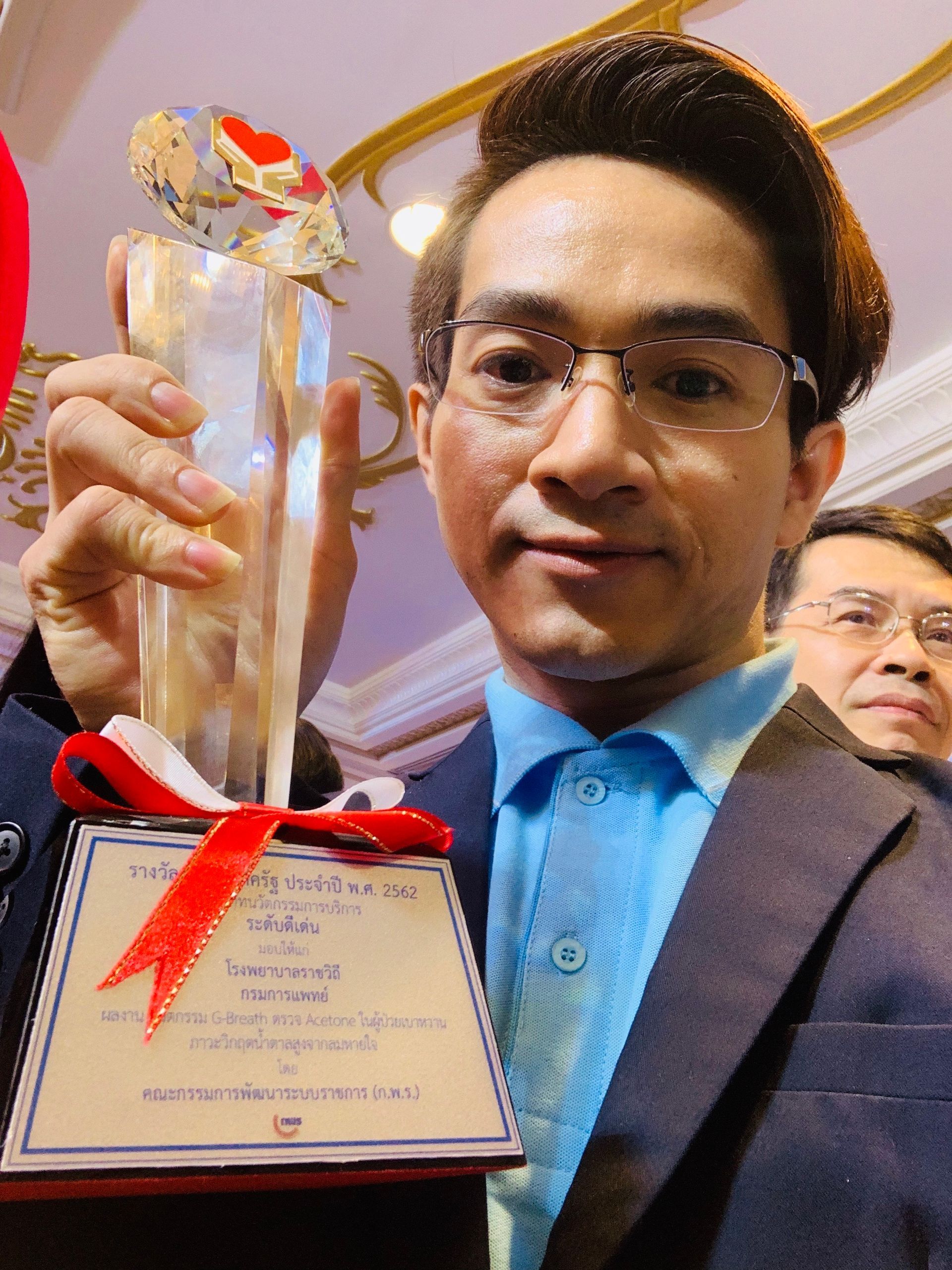 A man in a suit and glasses is holding a trophy