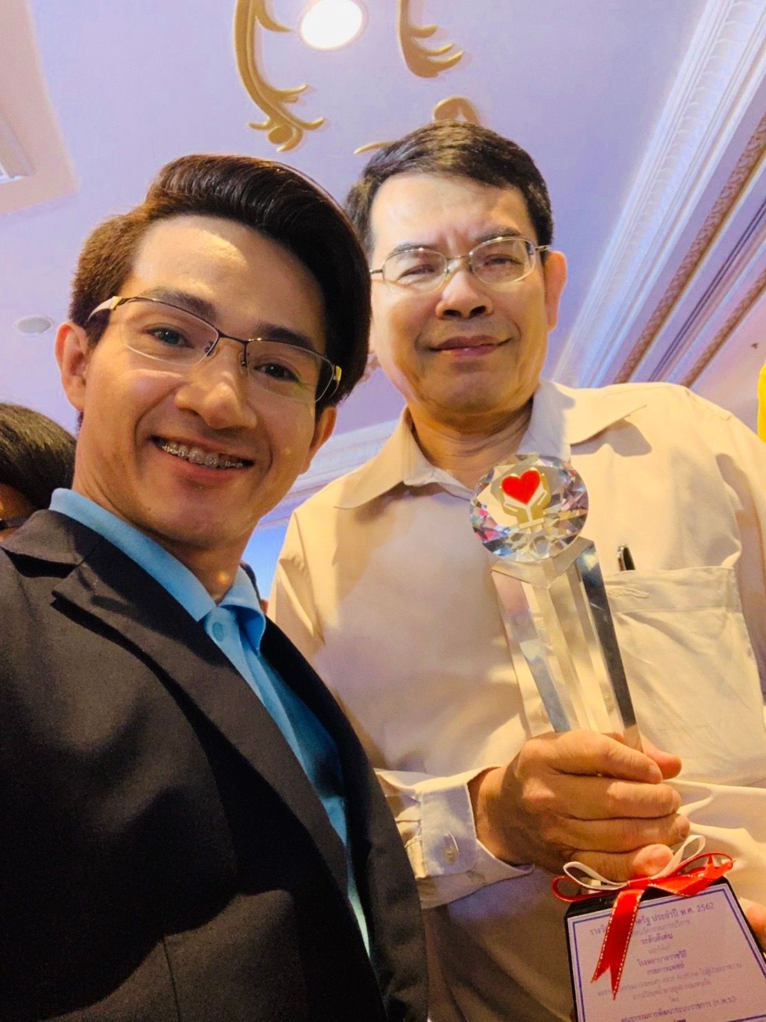 Two men are posing for a picture and one is holding a trophy