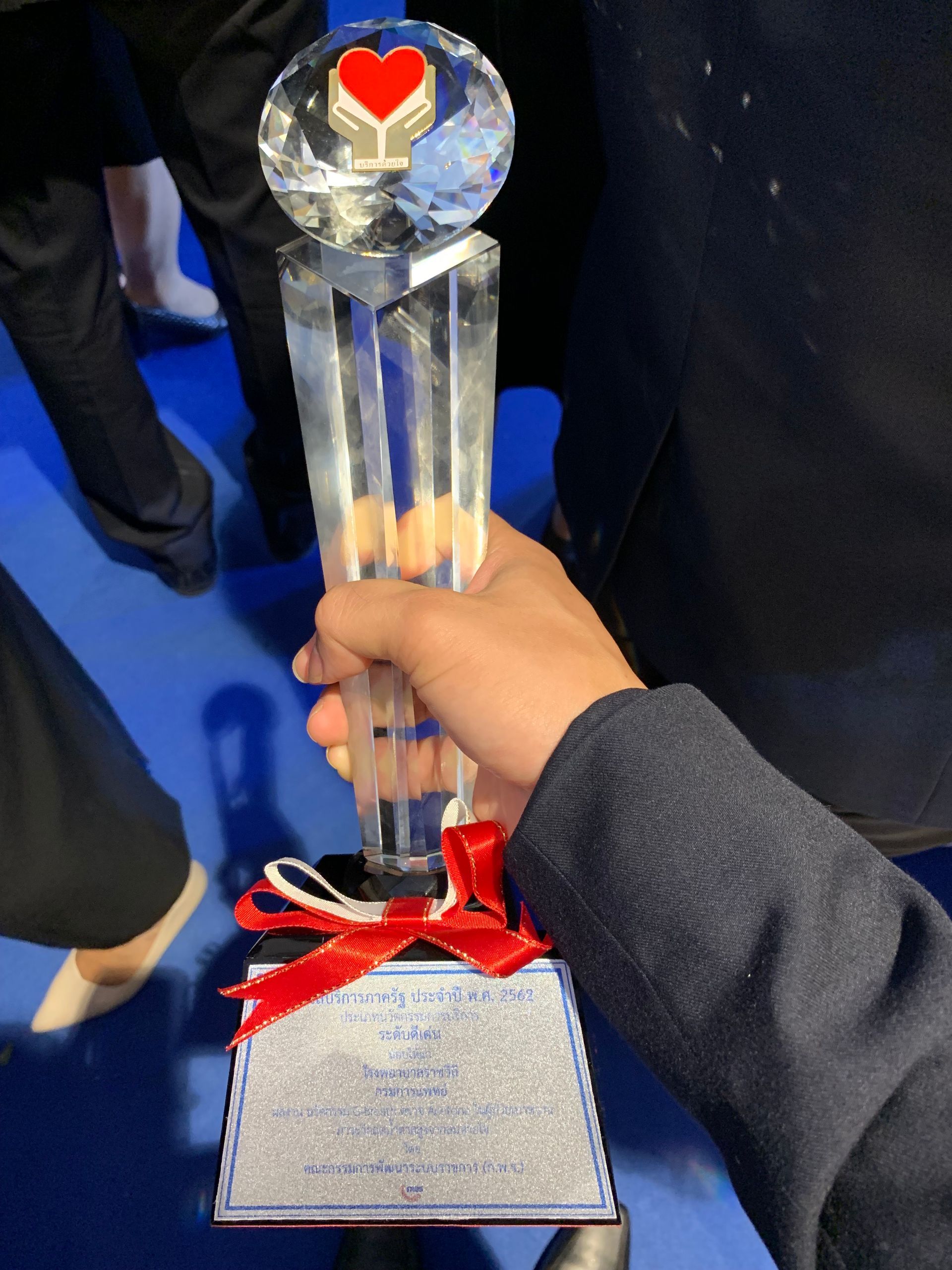 A person is holding a trophy with a red heart on top