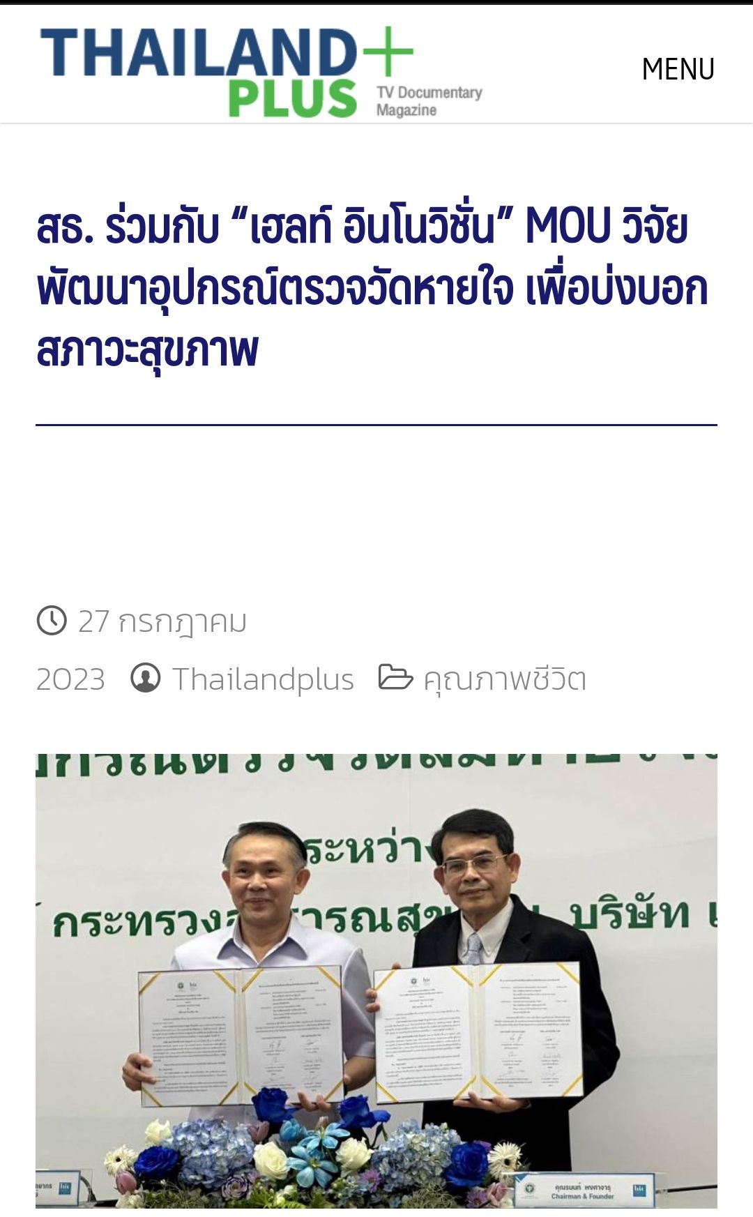 Two men are holding a document in front of a white board.