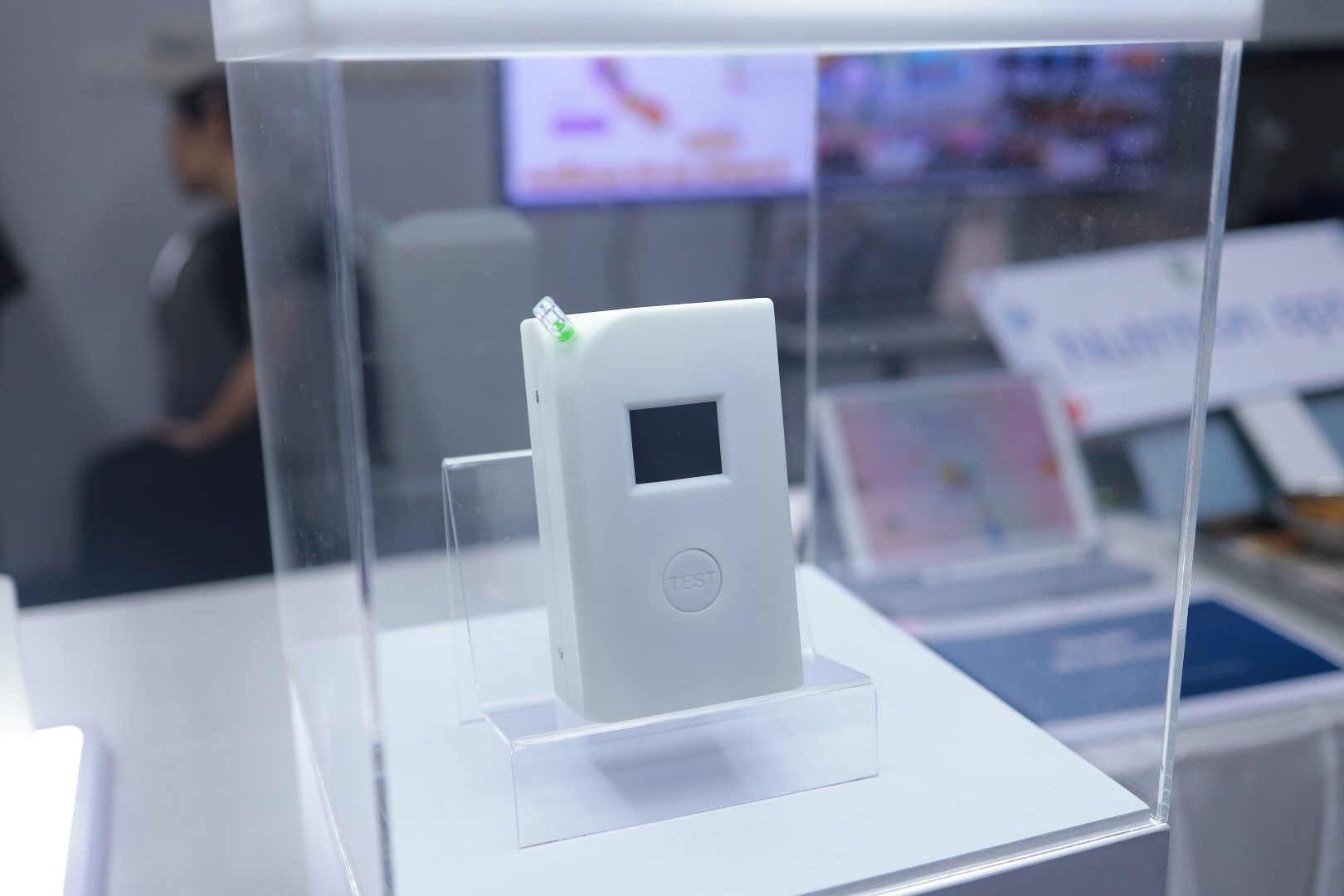 A small white device is sitting in a clear display case.