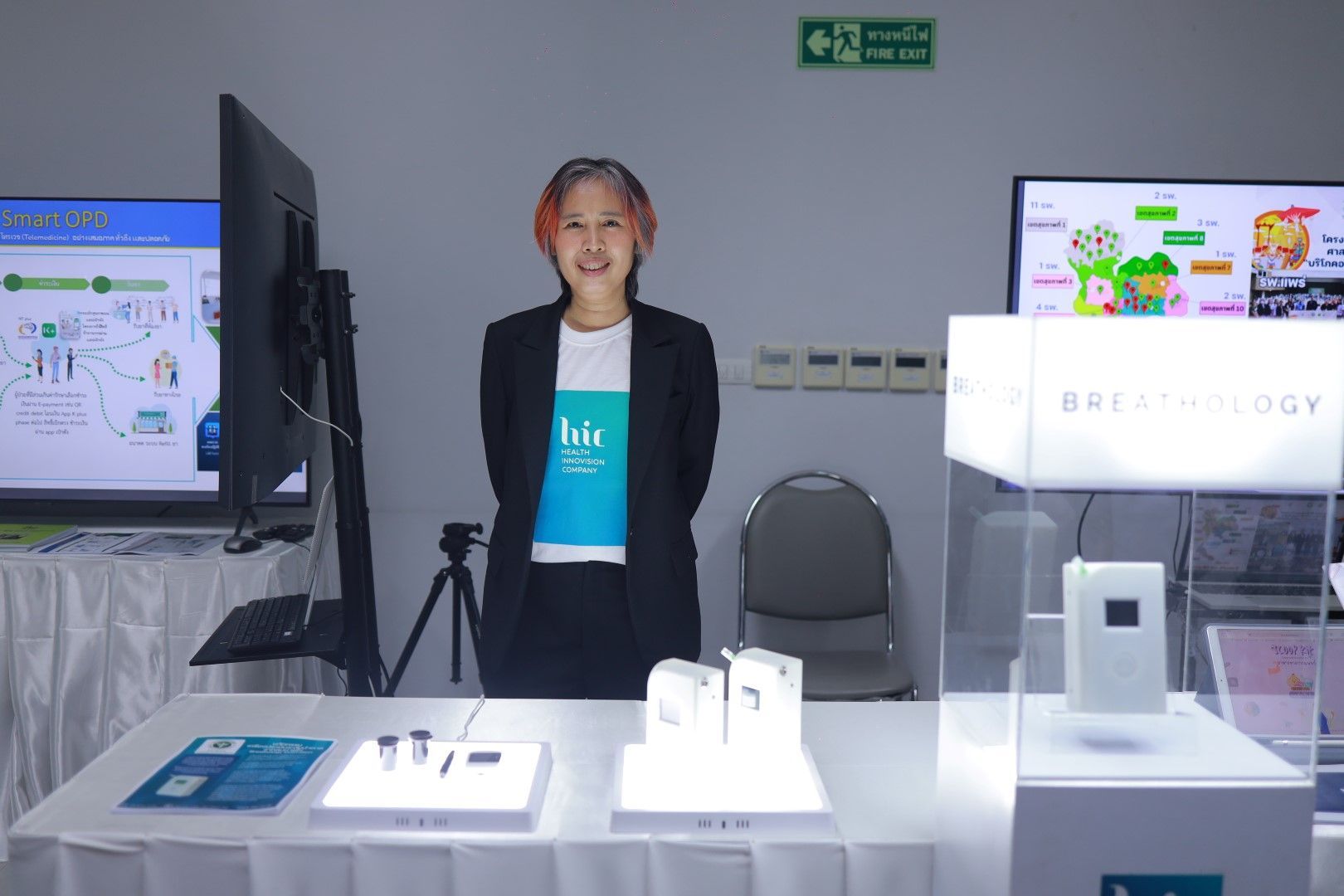 A woman is standing in front of a table with a tv on it.