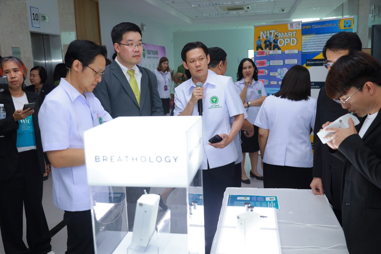 A group of people are standing around a table with a box that says breathology on it.