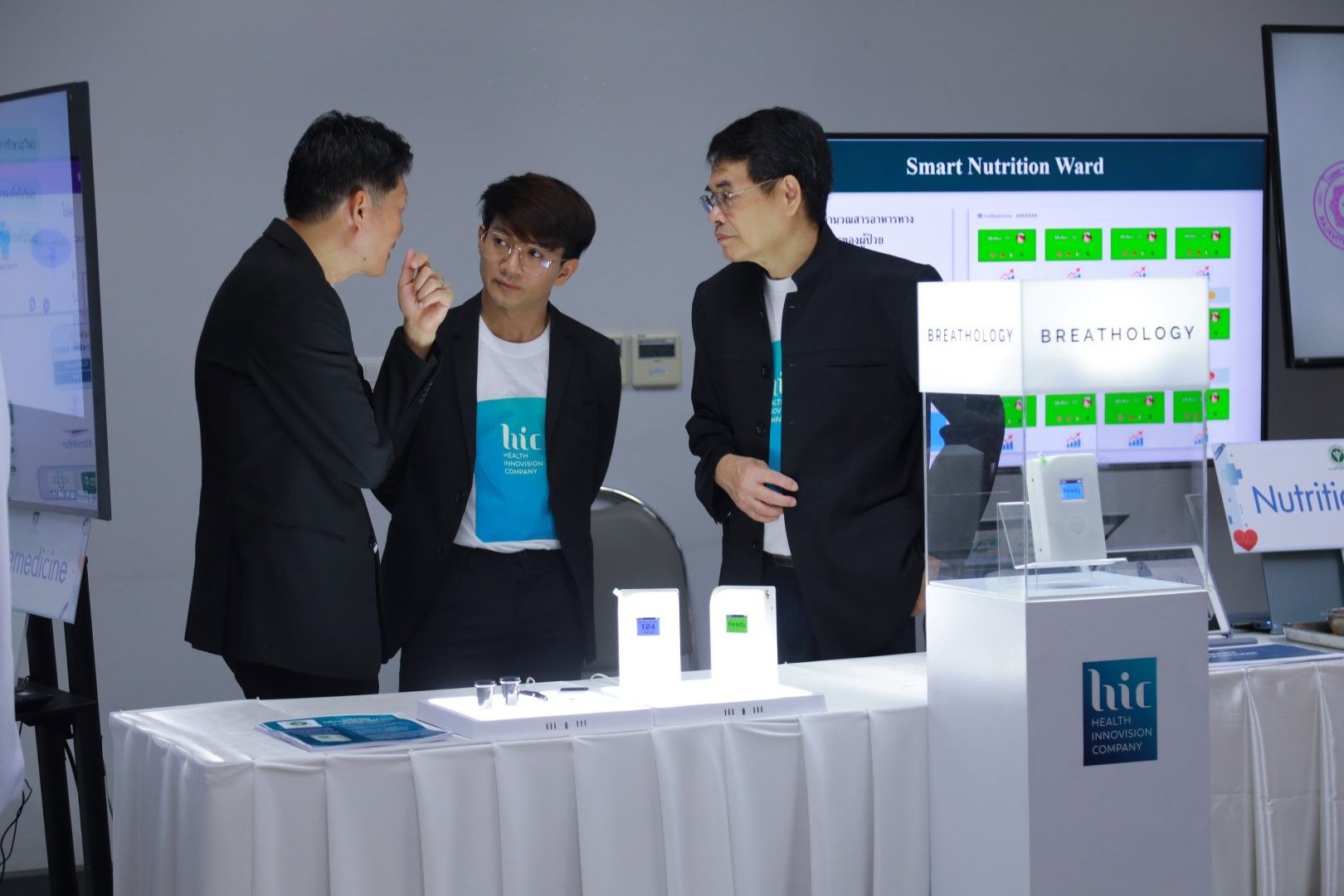 A group of men are standing around a table talking to each other.