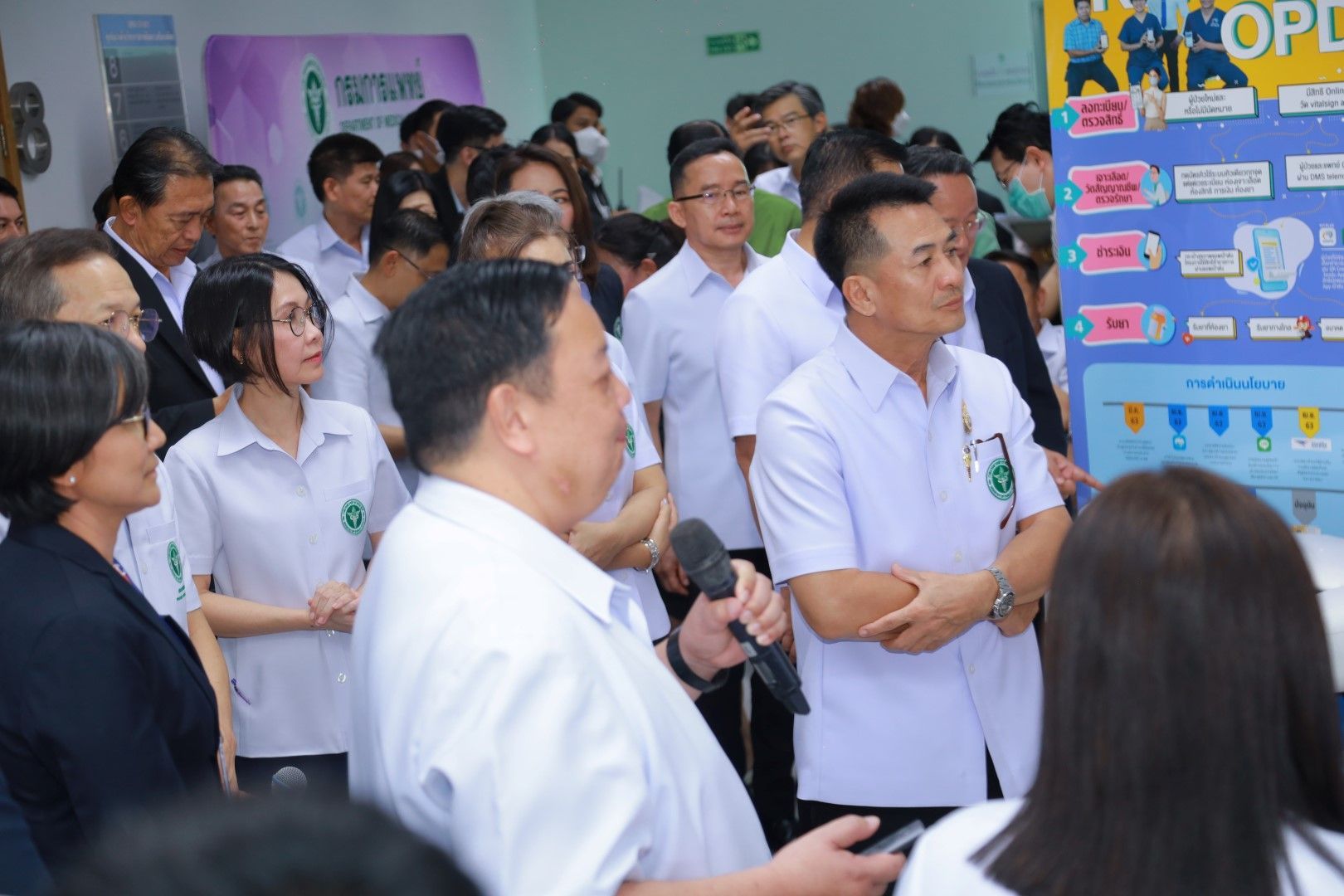 A group of people are standing in a room talking to each other.