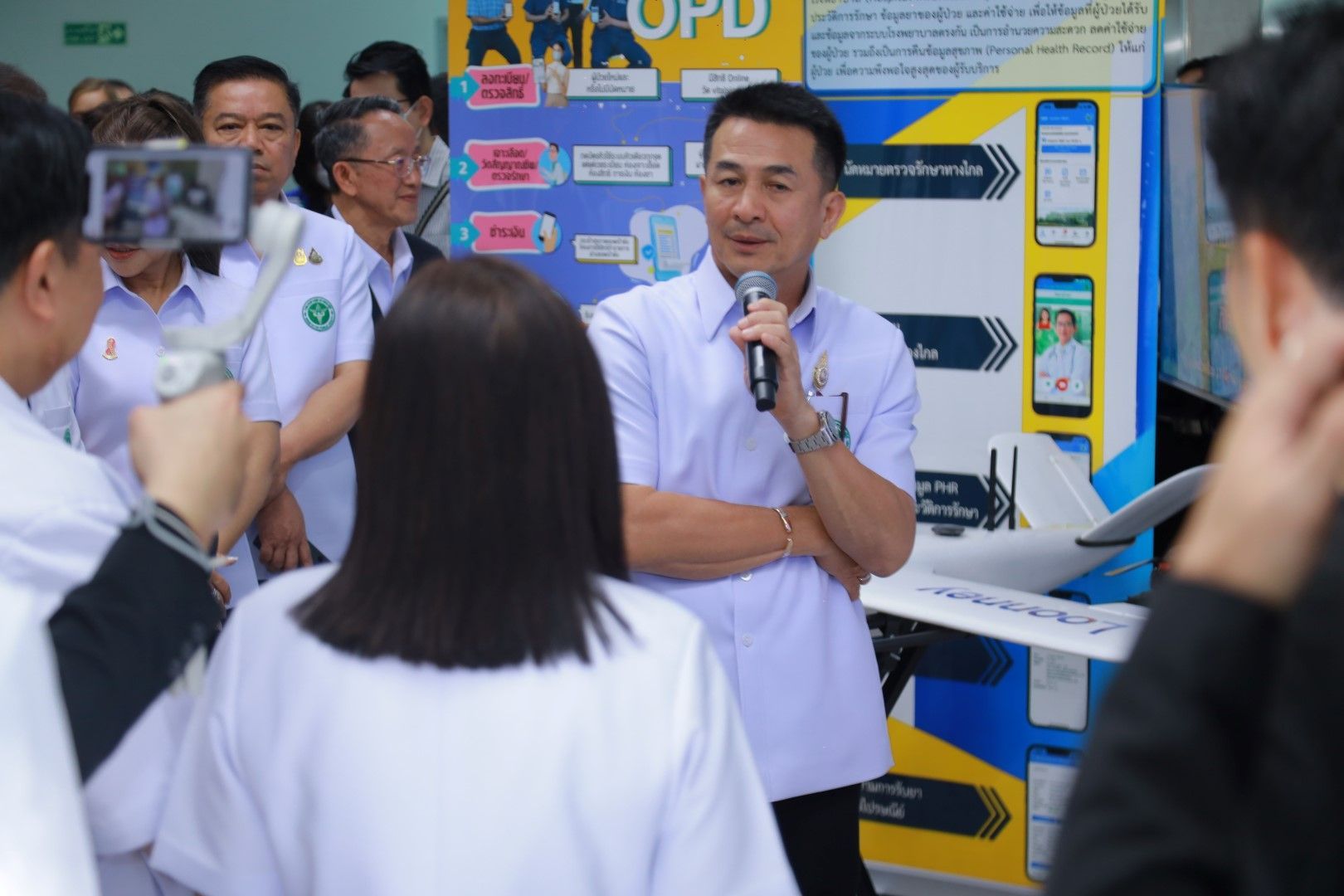 A man is talking into a microphone in front of a group of people.