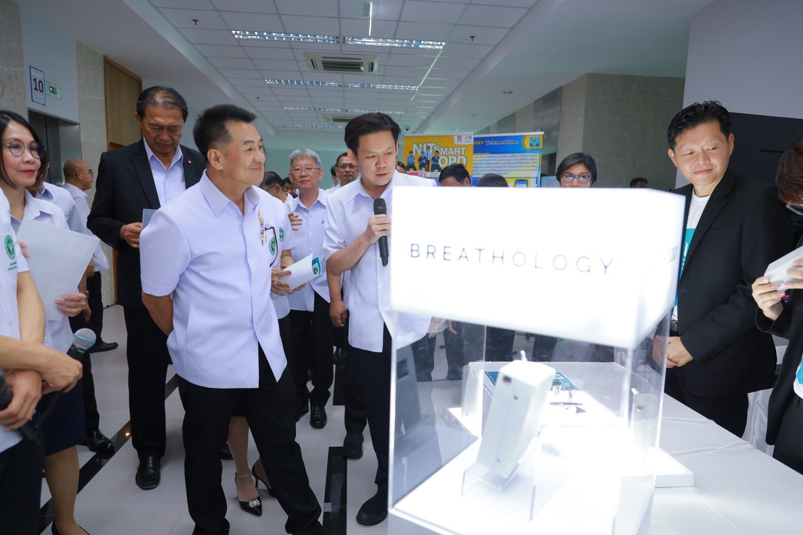 A group of people are standing around a table with a sign that says breathology.