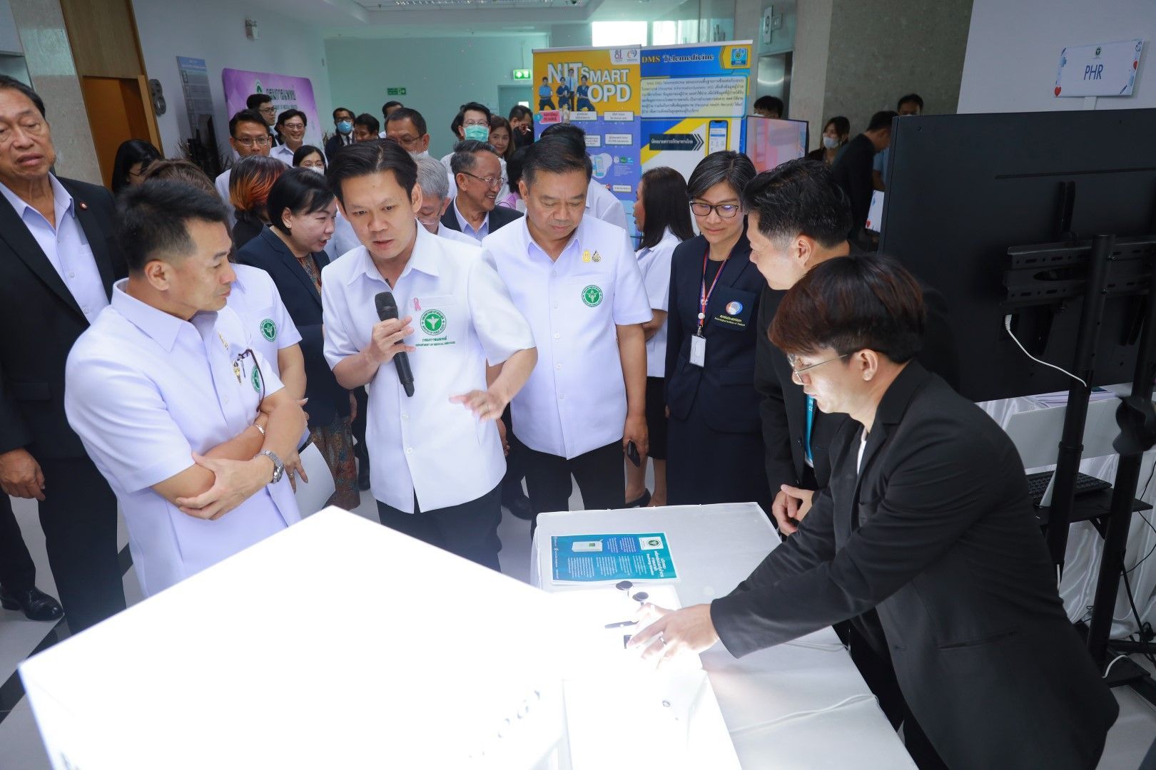 A group of people are standing around a table looking at something.