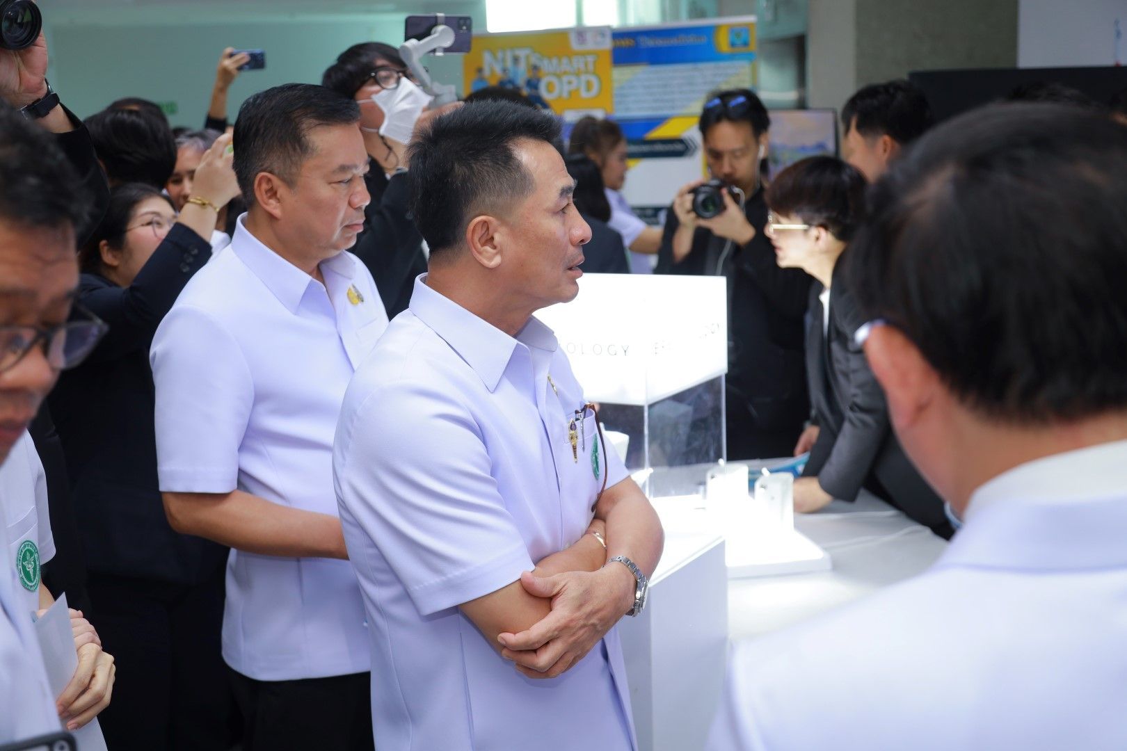 A man in a white shirt is standing in a crowd of people.