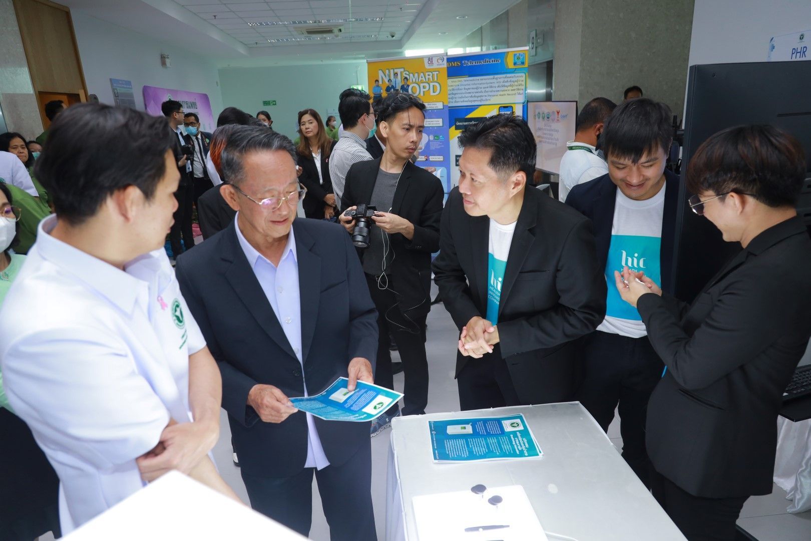 A group of people are standing around a table talking to each other.