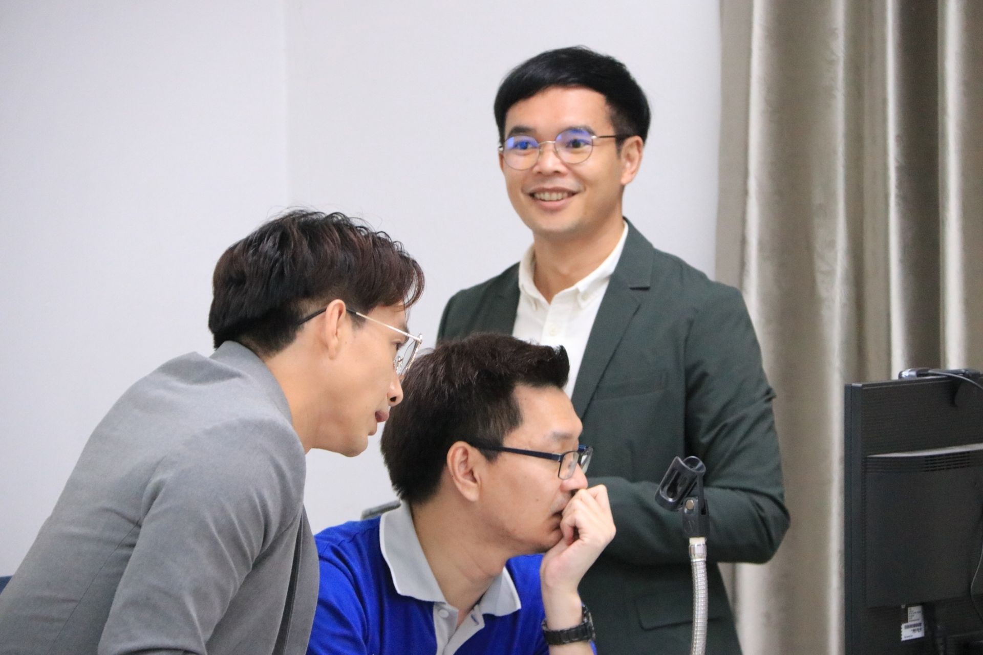 A group of men are looking at a computer screen together.