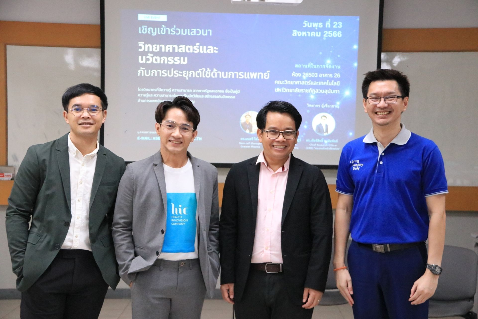A group of men are posing for a picture in front of a projector screen.