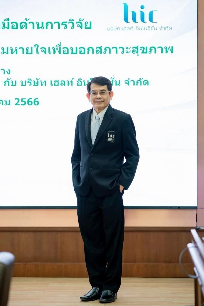 A man in a suit is standing in front of a projector screen.