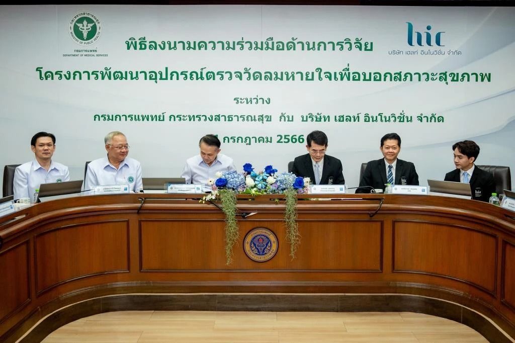 A group of men are sitting at a long wooden table.