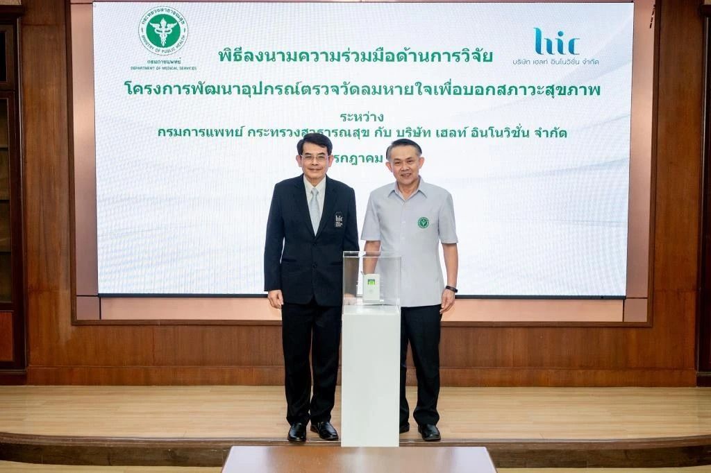 Two men are standing next to each other on a stage in front of a large screen.