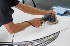 This is a picture of a man hard at work cleaning the hood of a car.