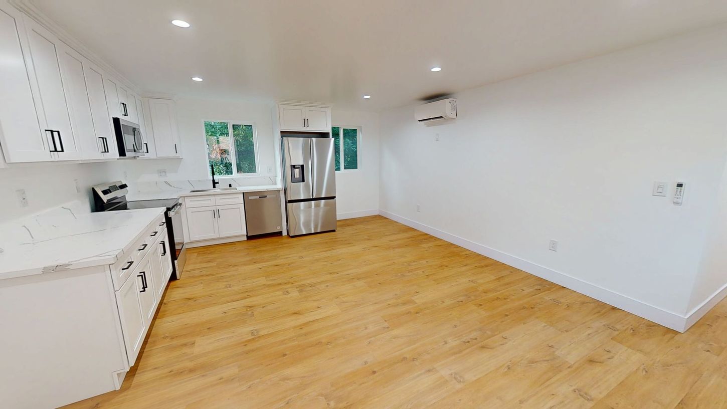 Bright kitchen with white cabinets, stainless steel appliances, and wood flooring.