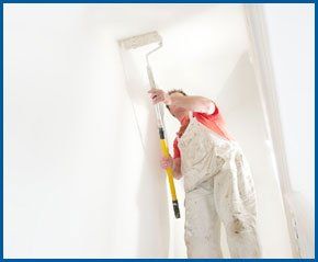  A professional painter and decorator painting a wall with a roller