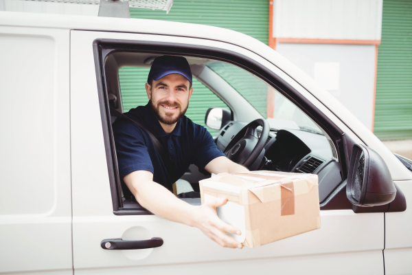 A delivery man is sitting in a van holding a cardboard box.