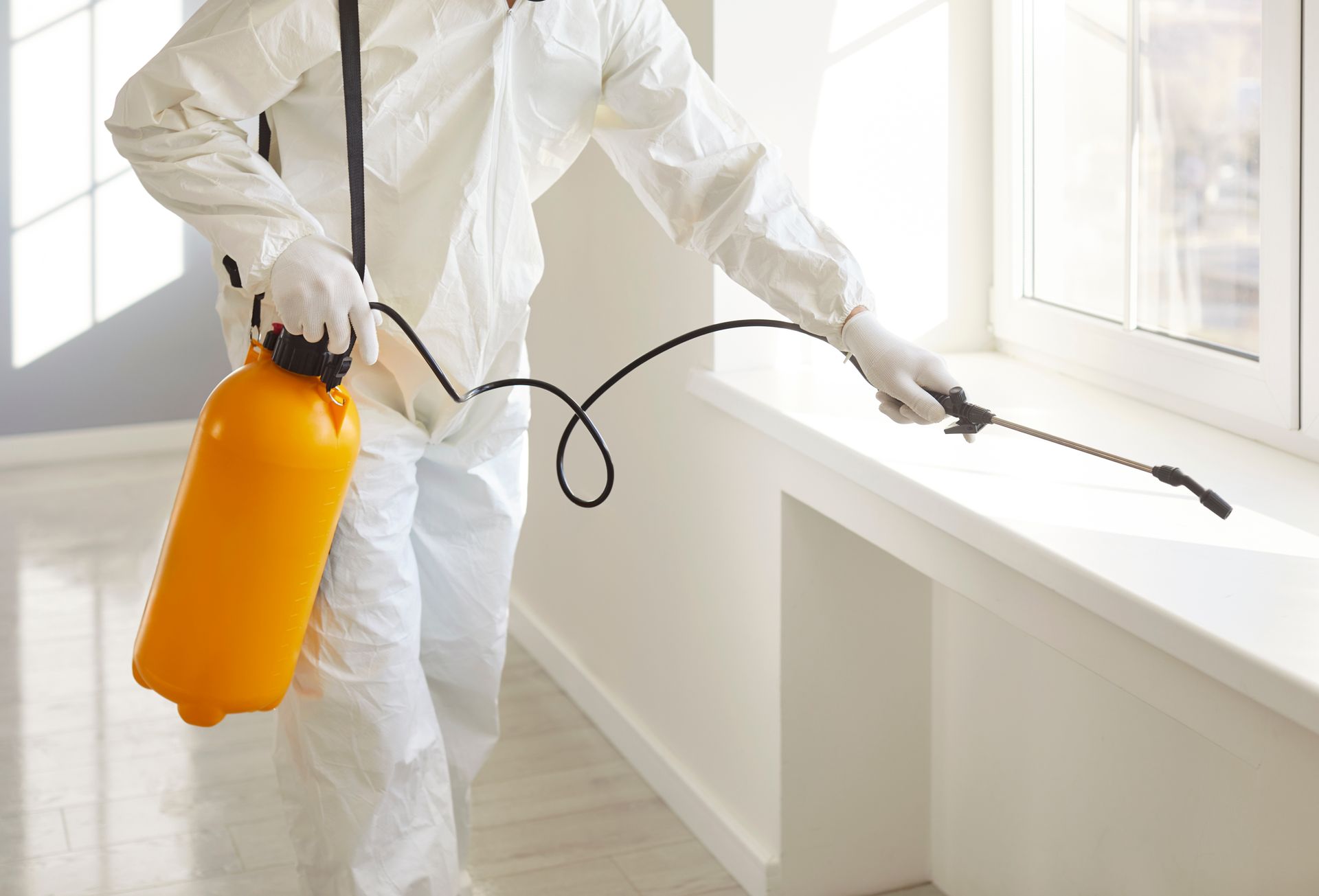 A technician in a white suit safely treating furniture using local pest control services.