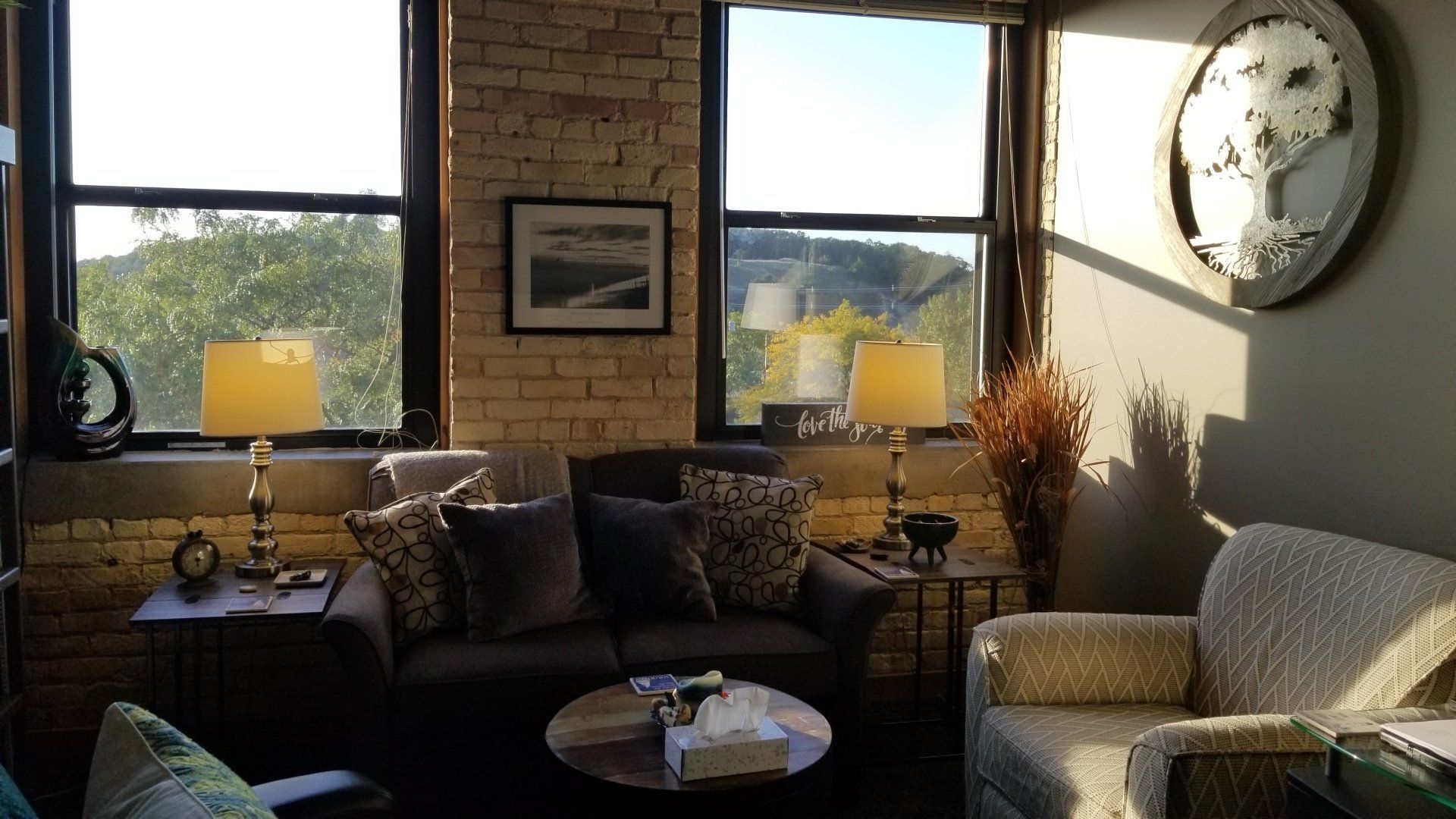 A living room with a couch and chairs and a clock on the wall