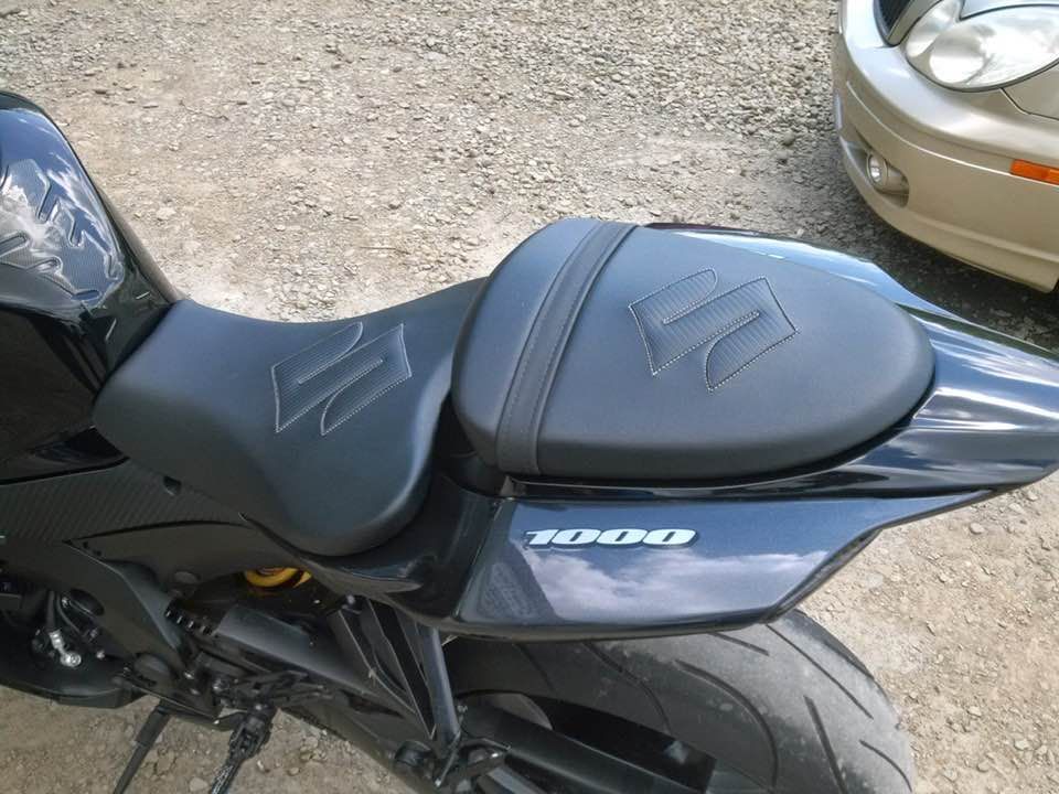 A black suzuki motorcycle is parked next to a car