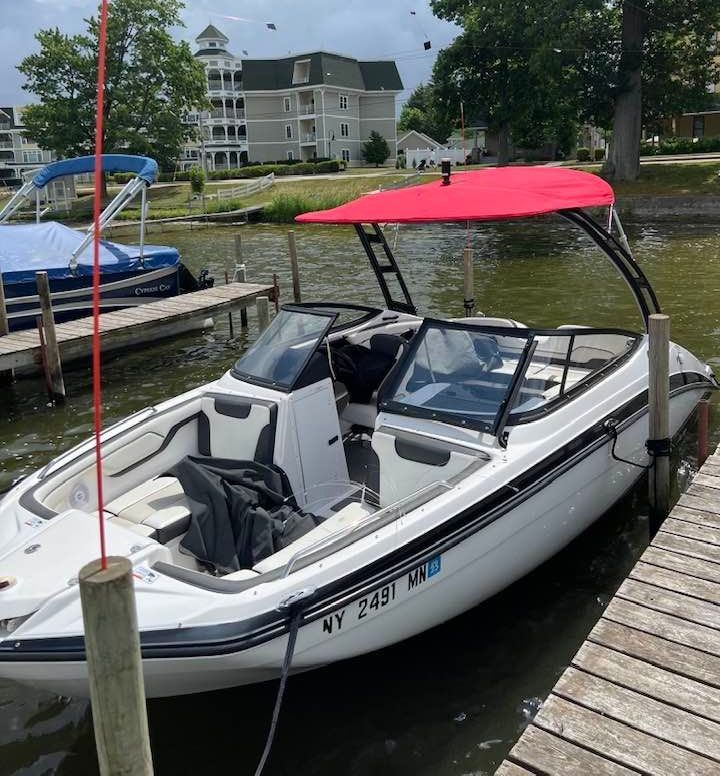 A white boat with a red canopy is docked at a dock