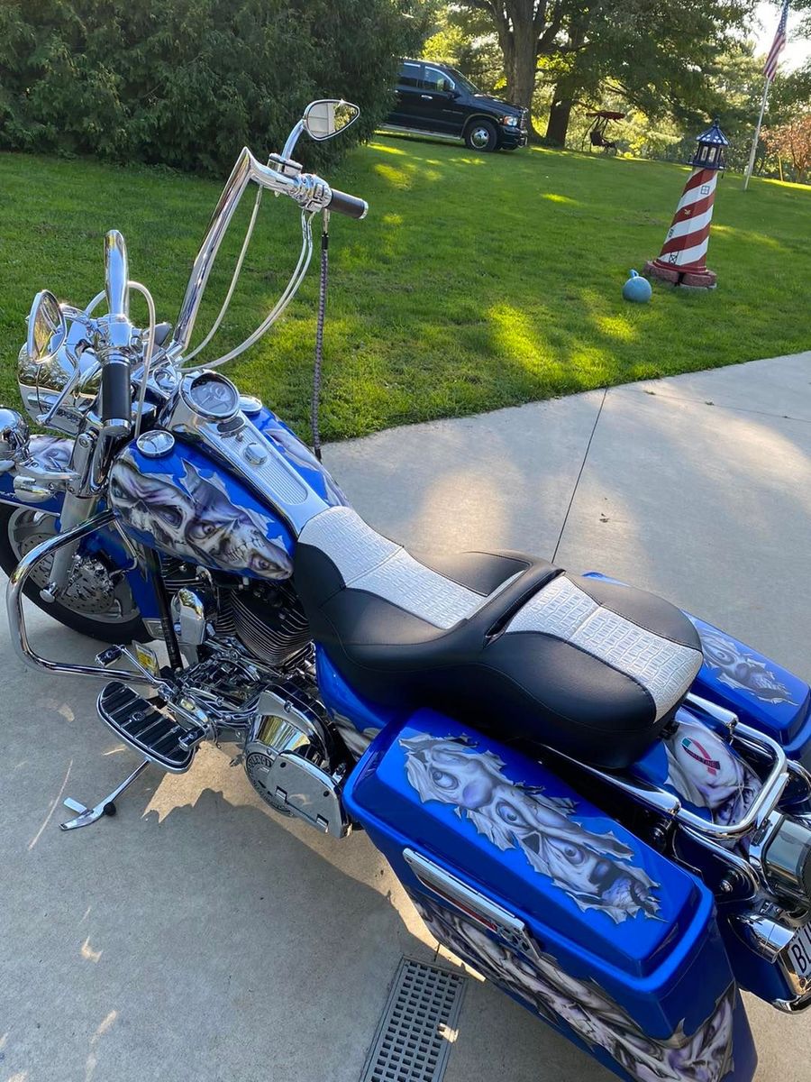 A blue and white harley davidson motorcycle is parked in a driveway.
