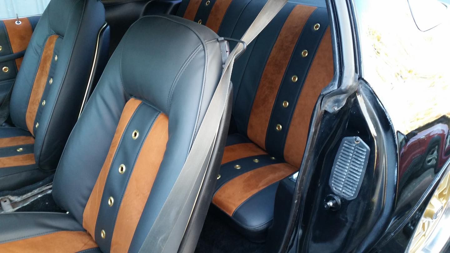 The interior of a black car with brown and black seats