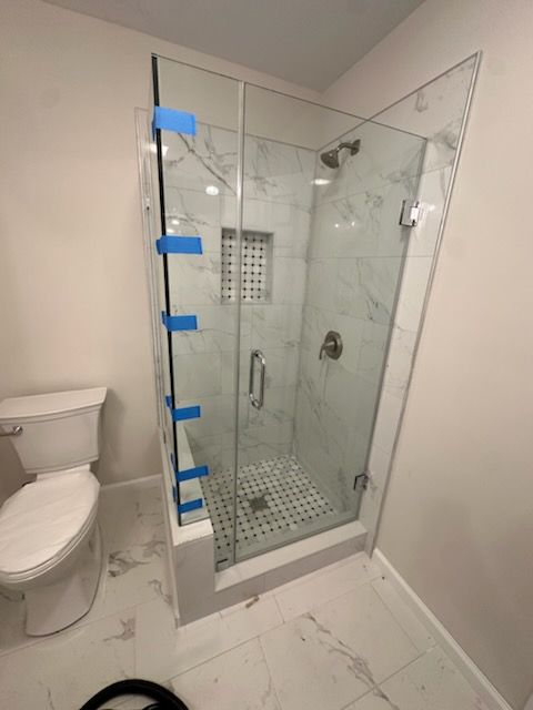 A bathroom with a toilet and a shower with a glass door.