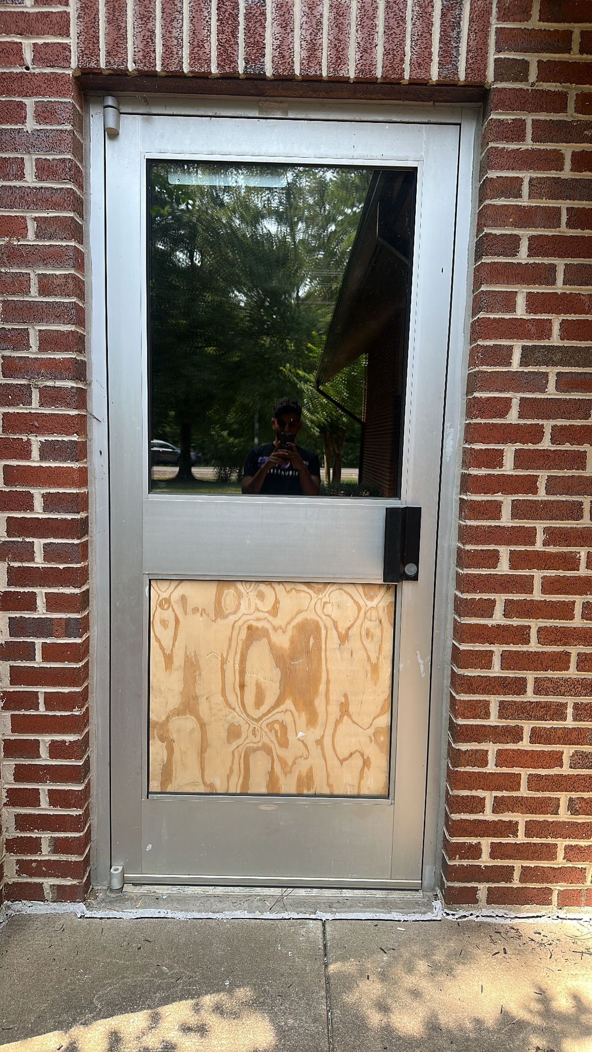 A stainless steel door with a brick wall behind it.