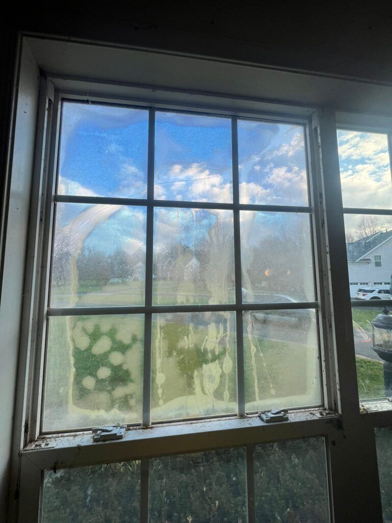 A dirty window with a blue sky behind it