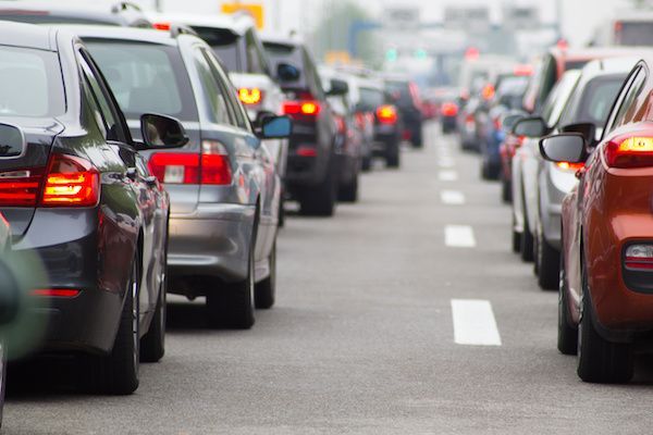 A rear-view perspective of a dense traffic jam on a multi-lane road with cars illuminated by red brake lights.