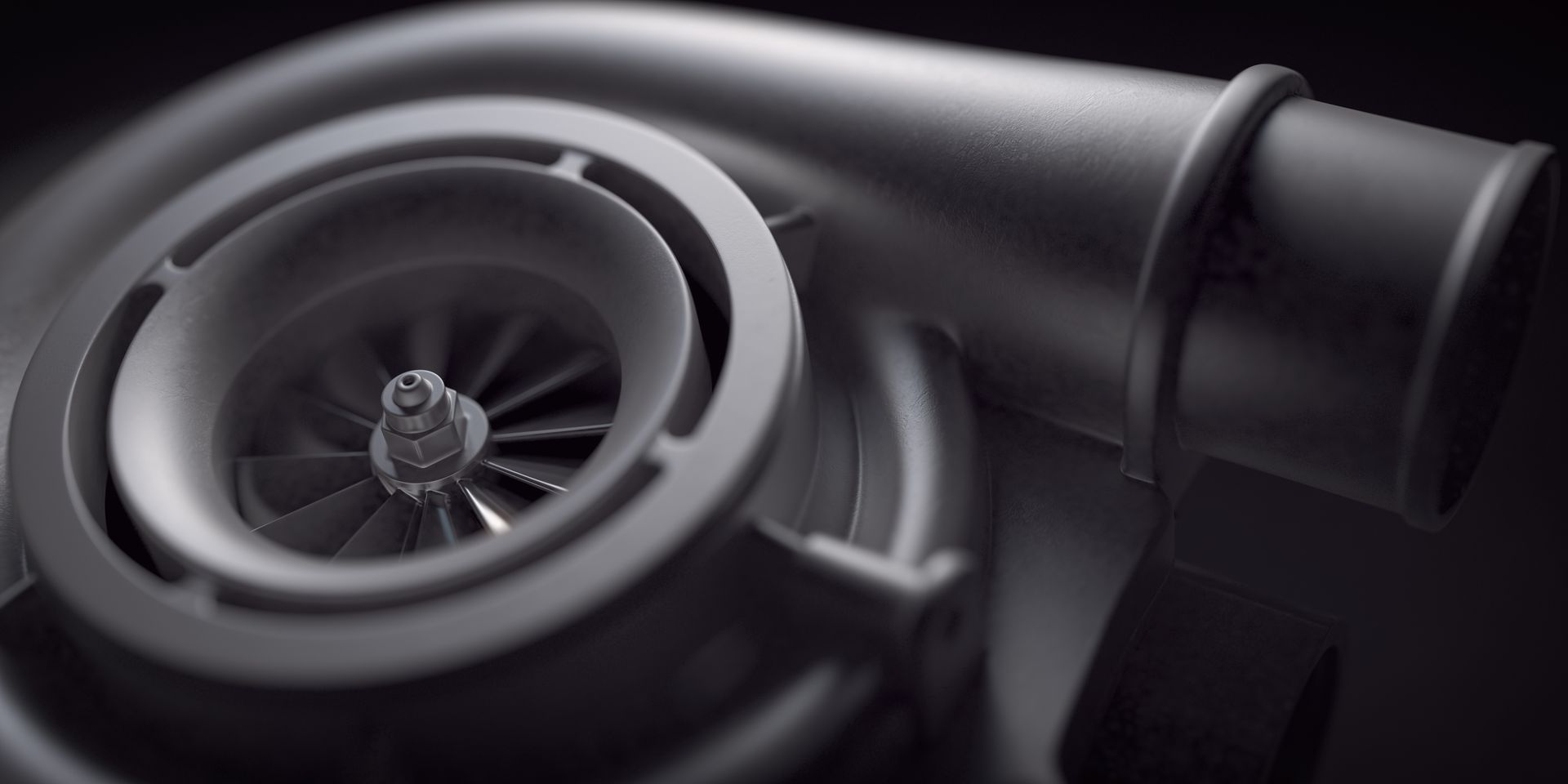 A close-up of a metallic automotive turbocharger showing the compressor wheel and intake housing against a dark background.