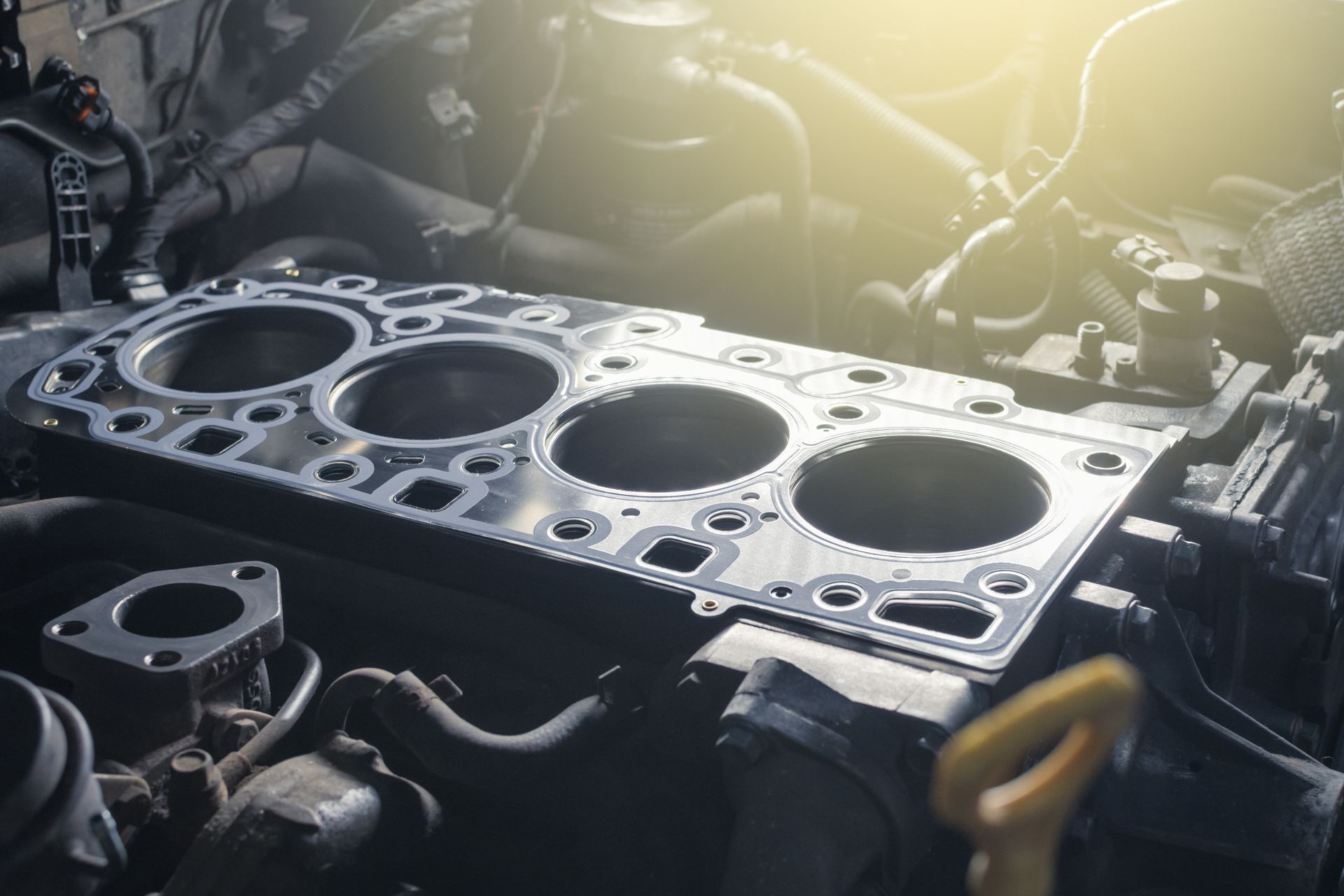 Open engine block of a car with four exposed cylinders and a head gasket installed.